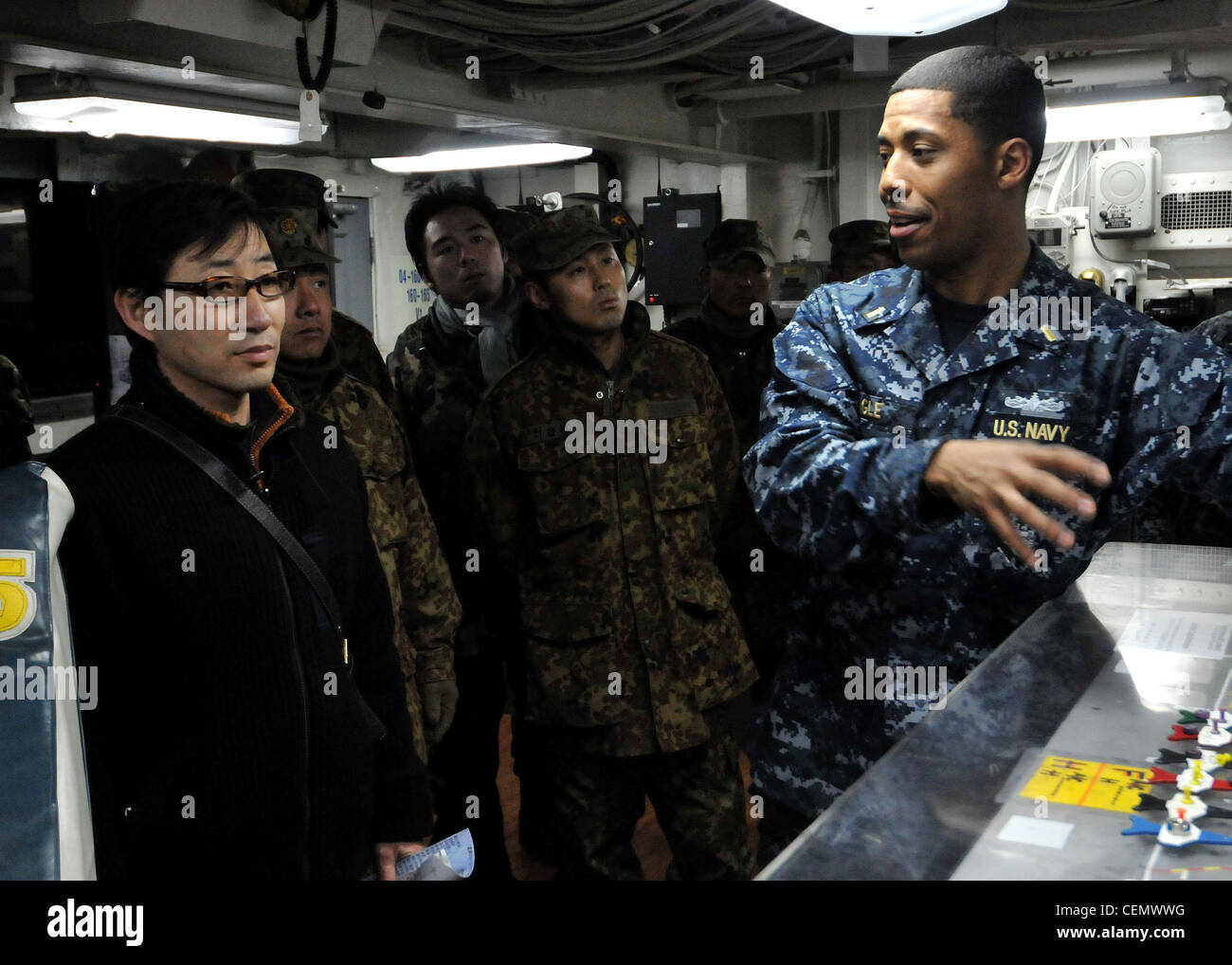 Ensign Derrick Ingle, assistant public affairs officer aboard the aircraft carrier USS George Washington (CVN 73), gives members of the 13th Infantry Regiment of the Japan Ground Self-Defense Force a tour of the ship's flight deck control. The guests were also able to tour the George Washington's hangar bay, navigation bridge and flight deck. Stock Photo