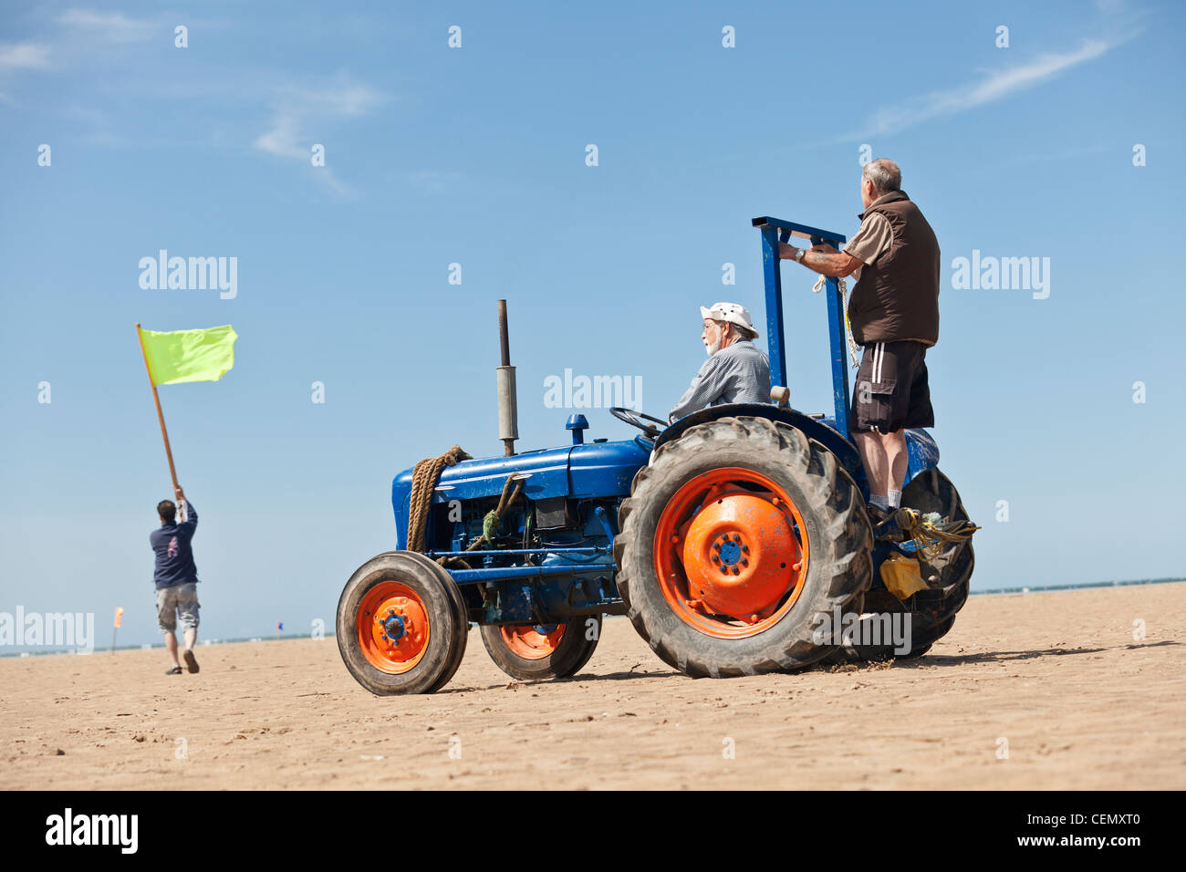 land yacht sailing race officials ride a tractor on the beach with flags preparing for a race Stock Photo