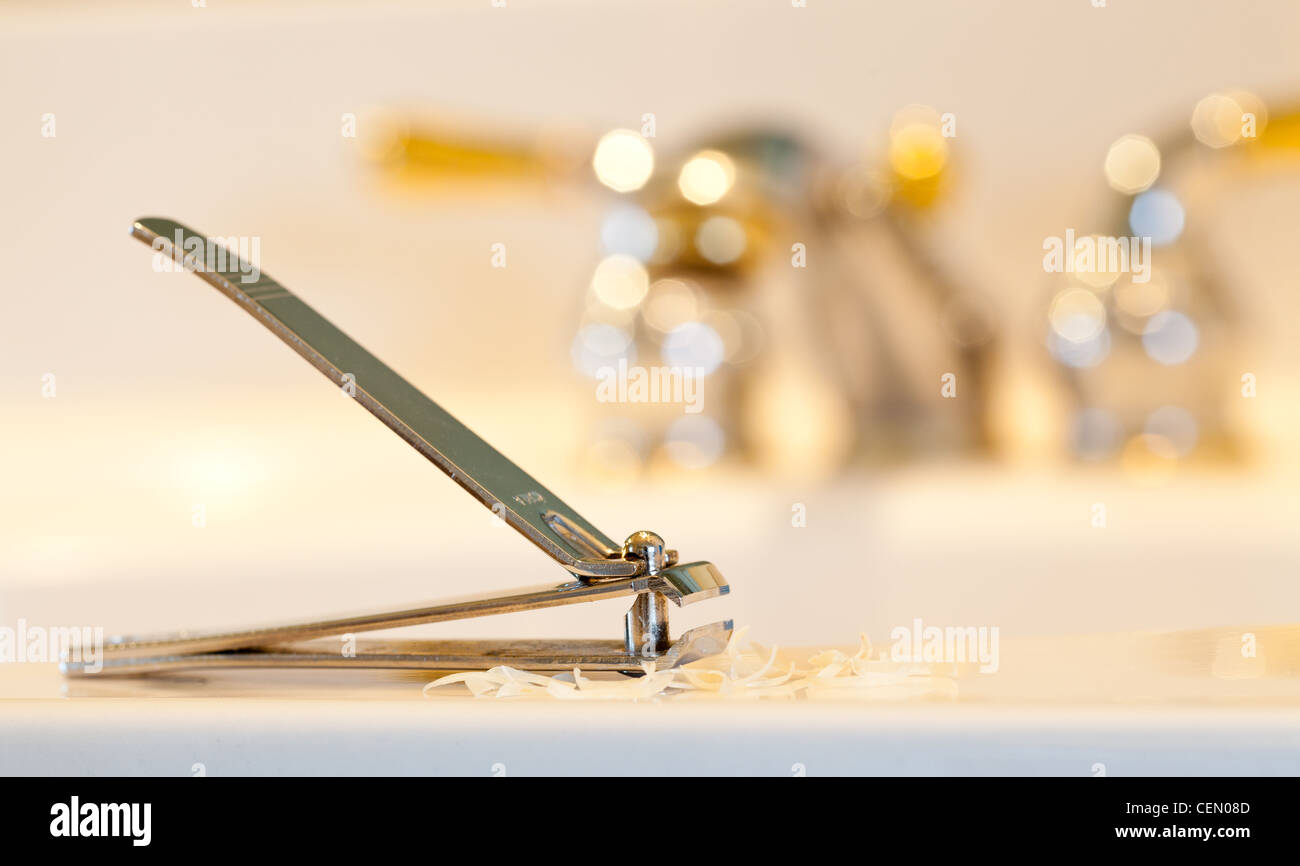 Finger nail clippings on bathroom sink with gold faucets or taps Stock Photo