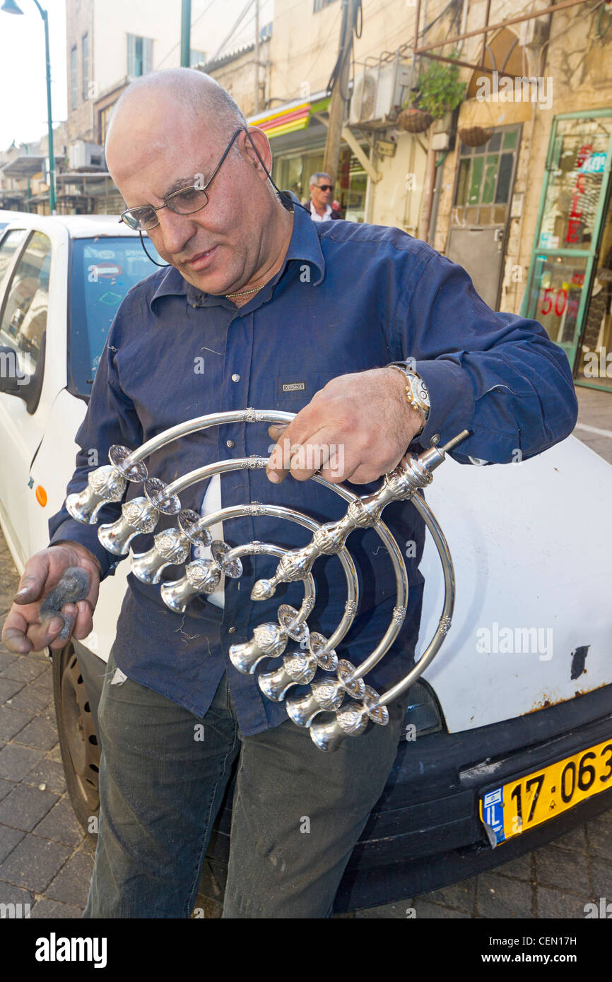 Local merchant polishes a Jewish menorah (used in Hanukkah celebrations) in the Jaffa flea market in Tel Aviv, Israel. Stock Photo