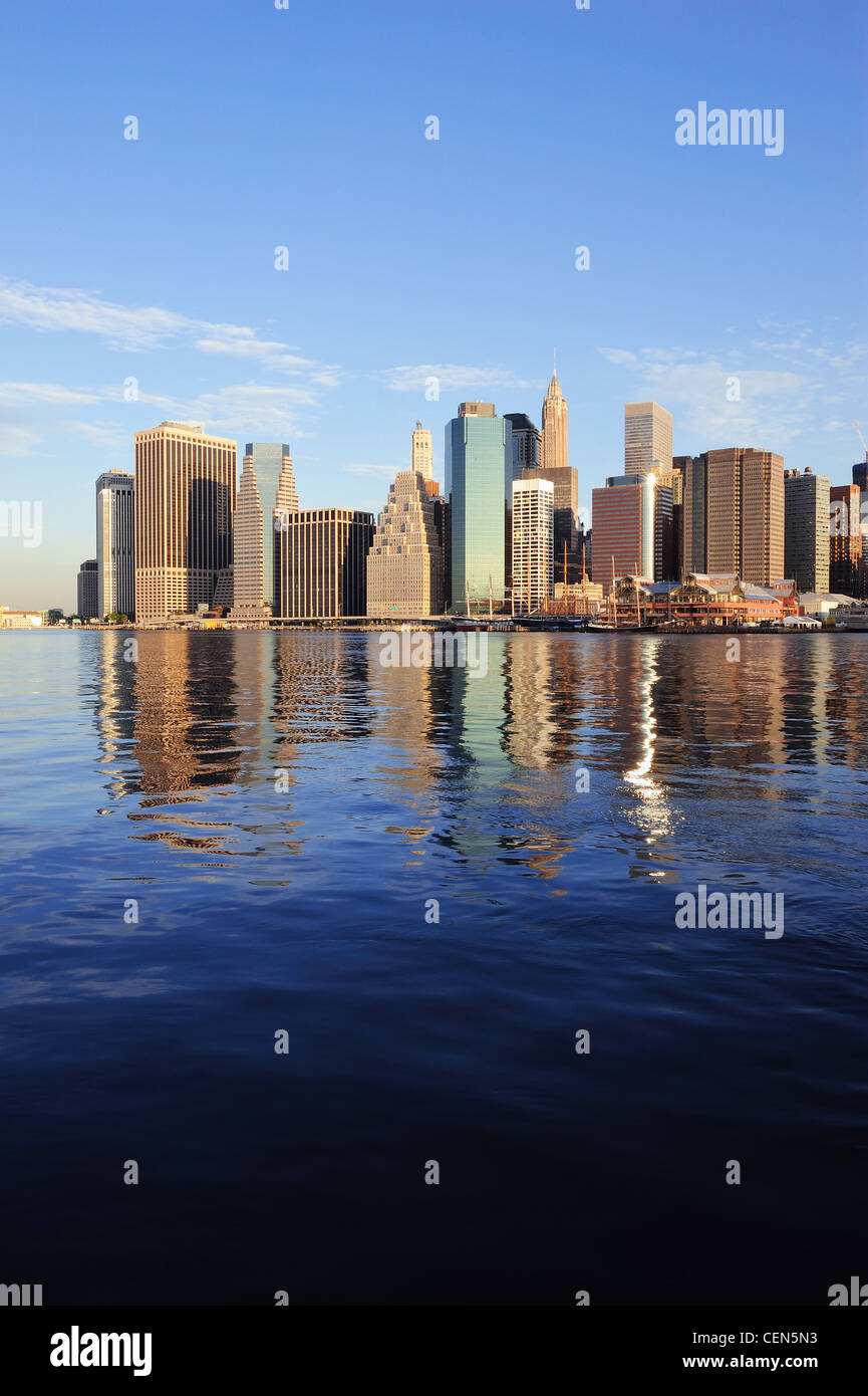 Lower Manhattan skyline panorama over East River with reflection and ...