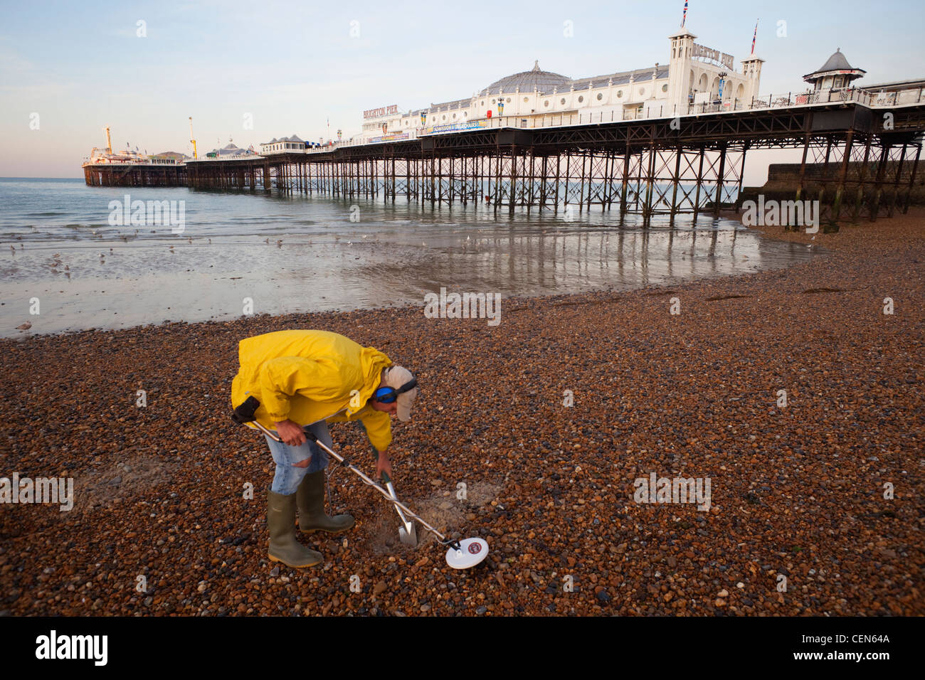 Man with metal detector on beach and brighton pier hires stock