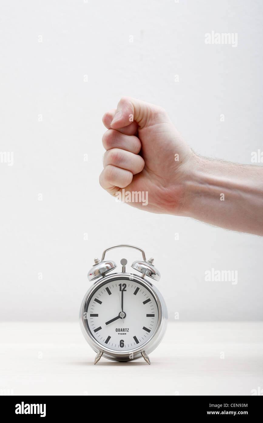 A hand breaking an alarm clock Stock Photo