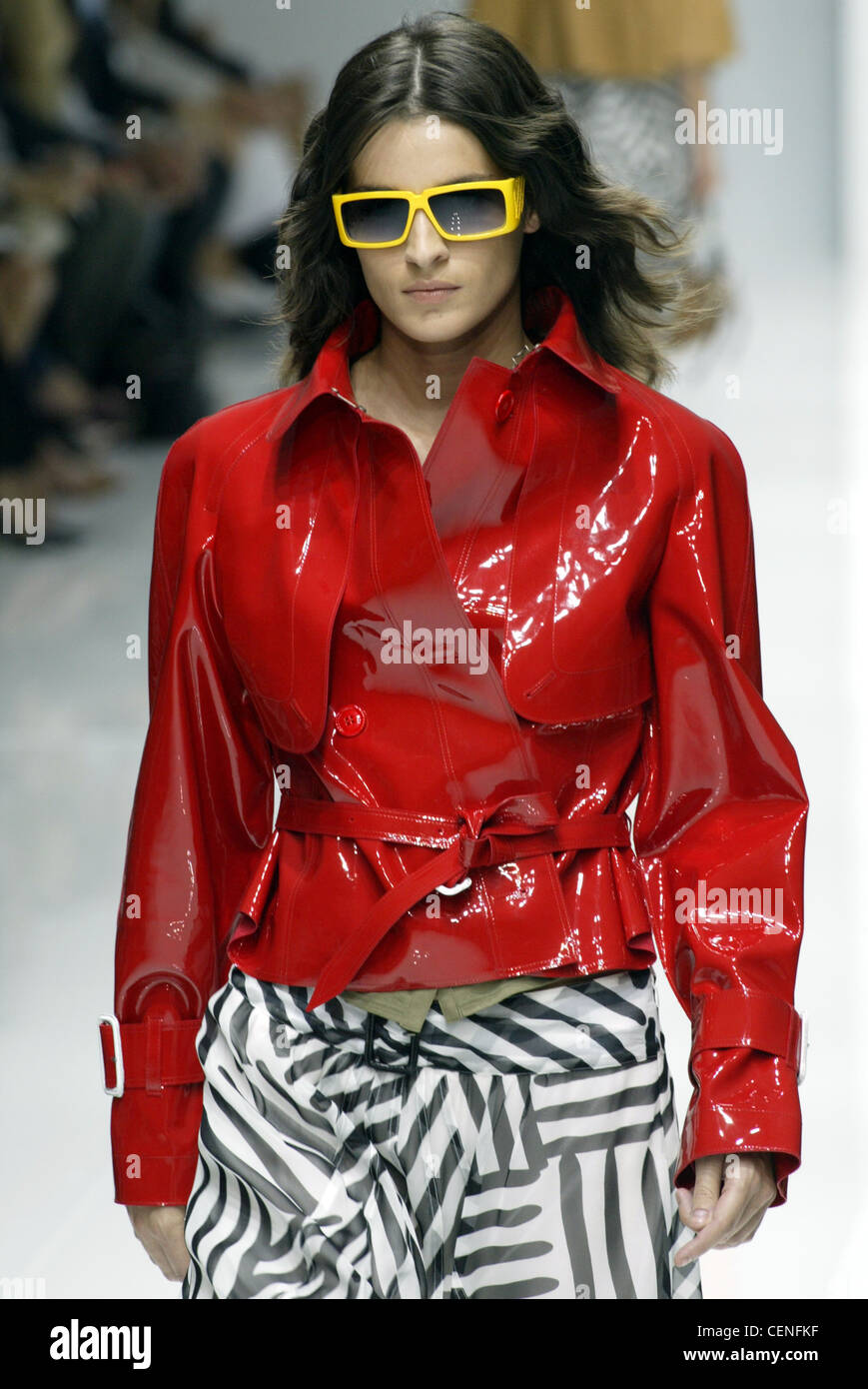 Burberry Milan Spring Summer Model long brunette hair wearing yellow frame  sunglasses, bright red patent leather short jacket Stock Photo - Alamy