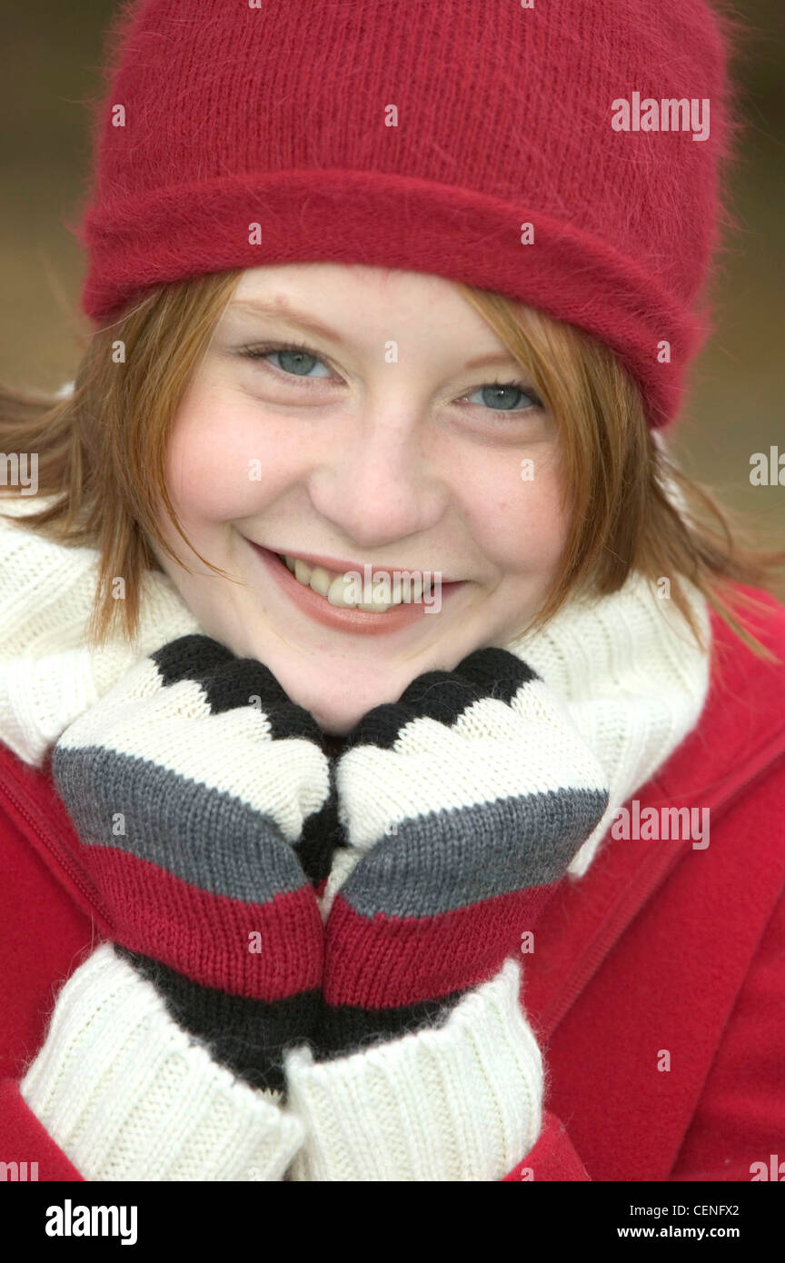 Female shoulder length red hair wearing red wool hat, white wool turtle neck jumper, red zip jacket and striped gloves, Stock Photo