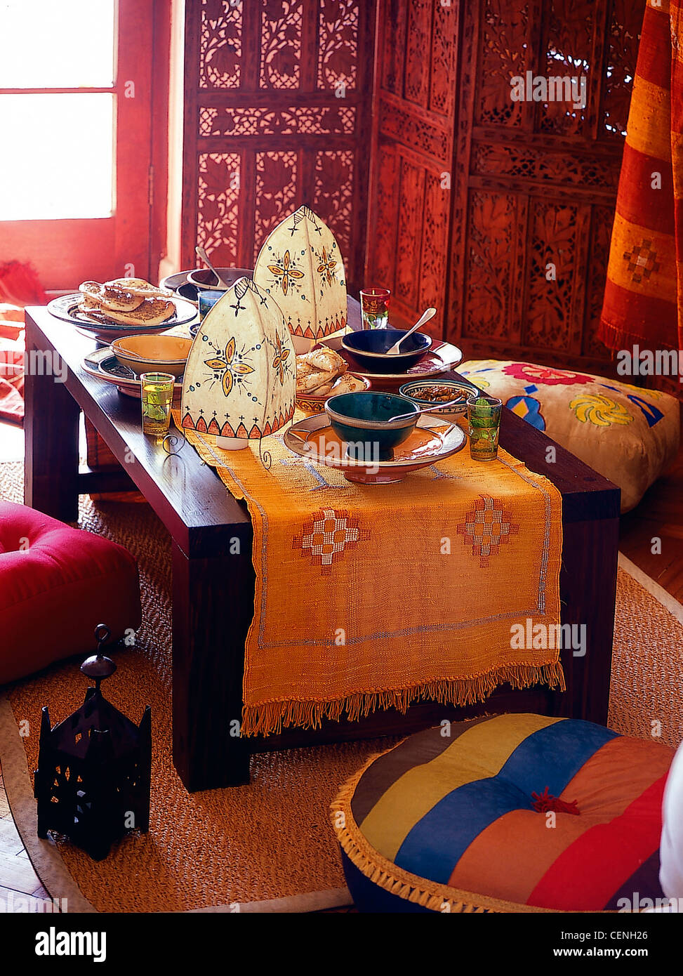 Moroccan Feast Low table patterned runner, decorated paper lanterns, bowls of moroccan food, large bright coloured flocushions Stock Photo