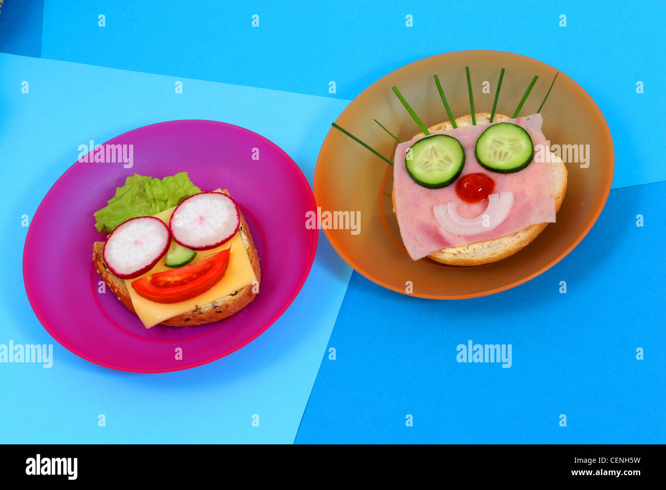 Two colourful plastic plates with open sandwiches on them with faces