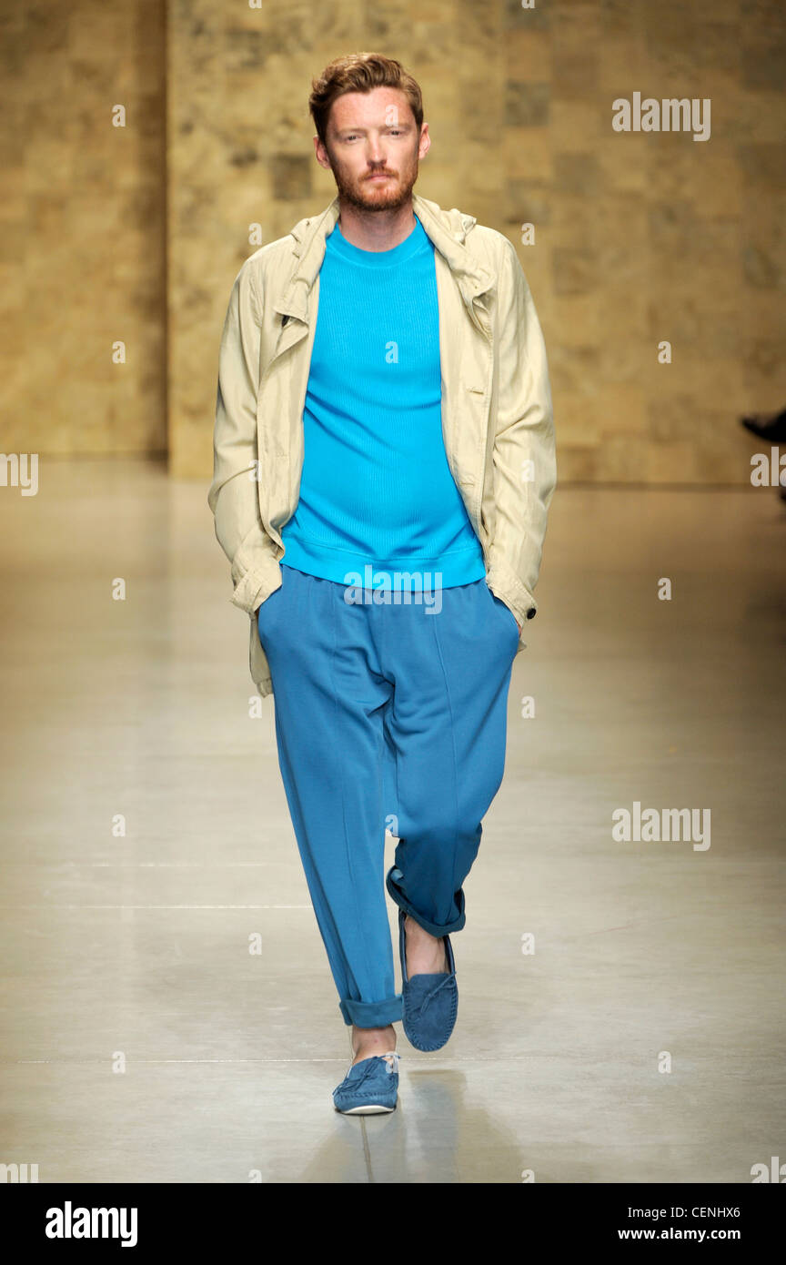 CP Company Milan Ready to Wear Spring Summer Cream jacket over blue t  shirt, turn up blue baggy trousers with blue suede boots Stock Photo - Alamy