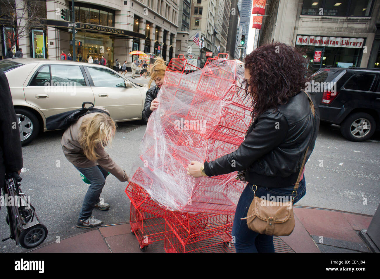 Women attempt to maneuver a cart of baskets through the city streets Stock Photo