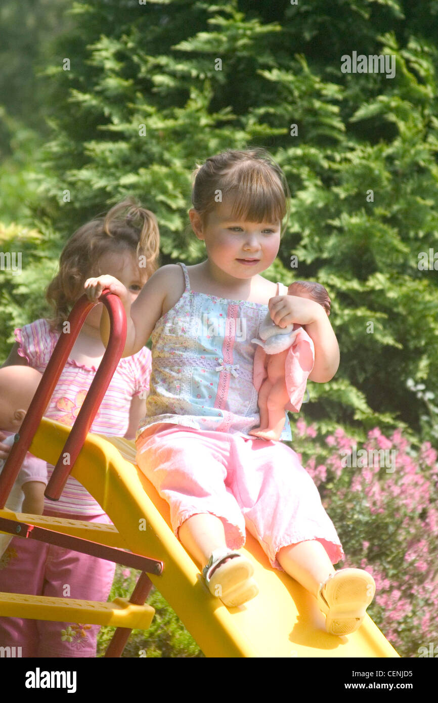 https://c8.alamy.com/comp/CENJD5/two-female-children-playing-on-slide-in-garden-one-sitting-on-top-CENJD5.jpg