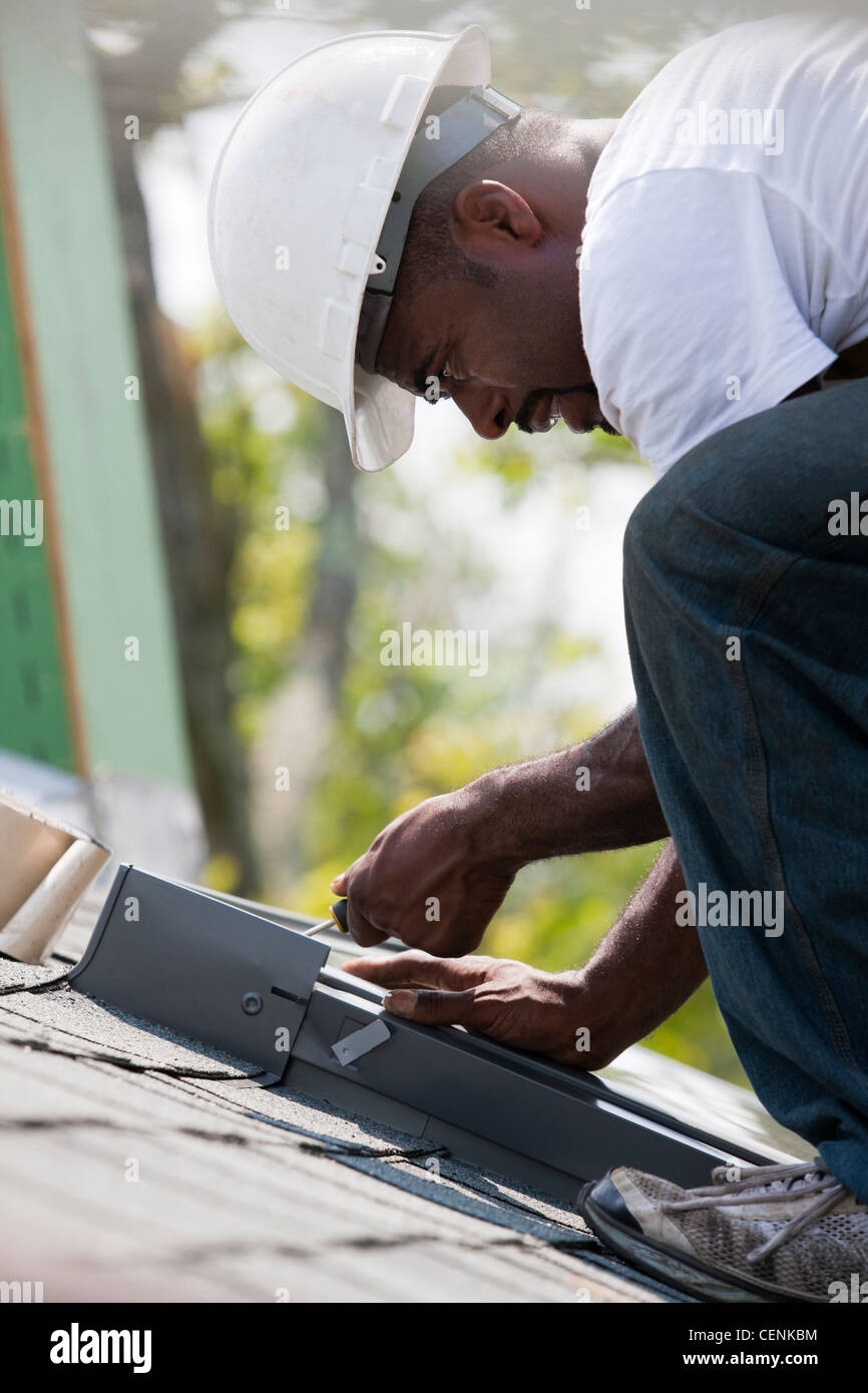 Carpenter attaching flashing around skylight on the new roof Stock Photo