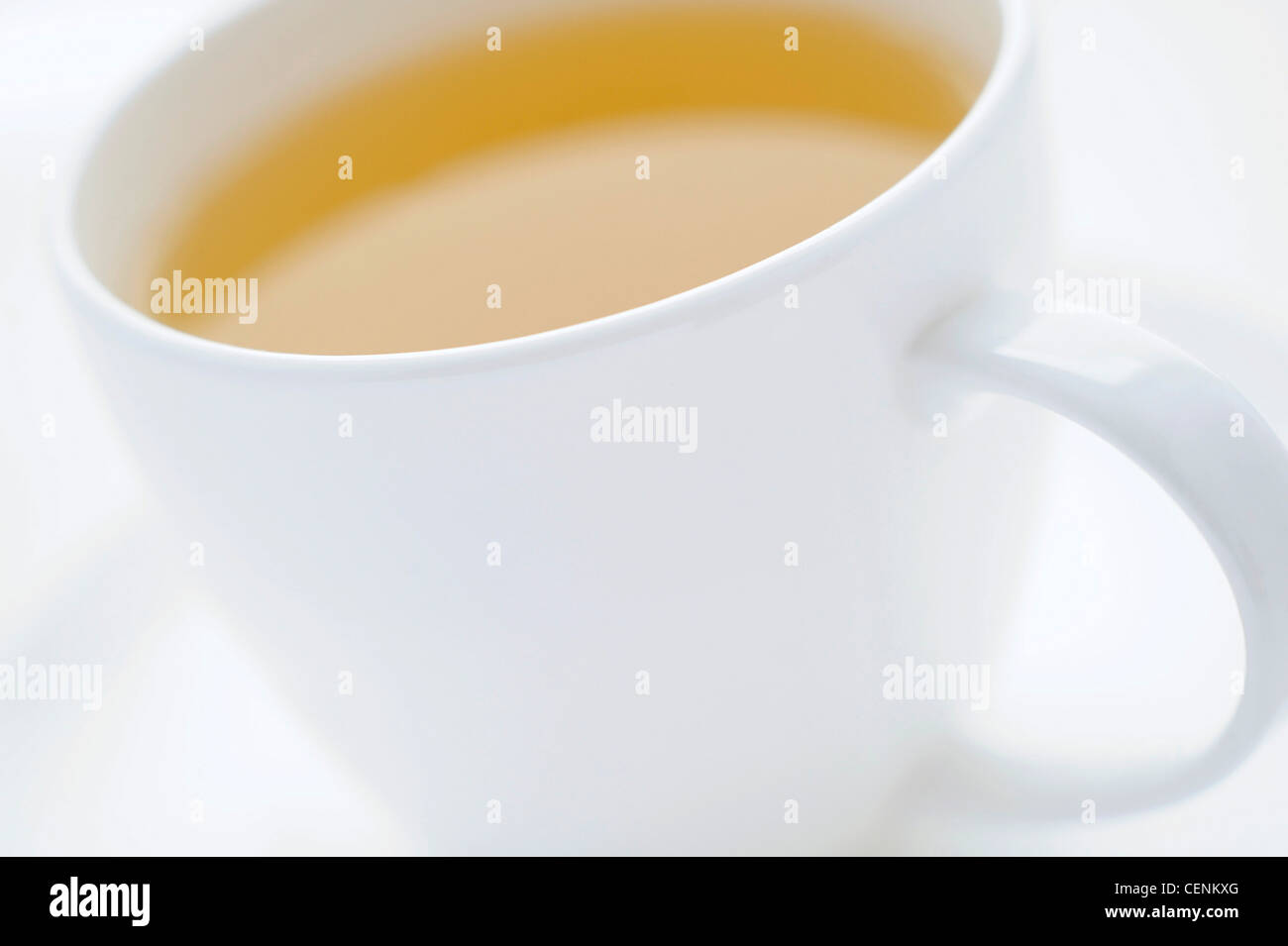 A close up of a white cup and saucer filled with a yellow fruit tea Stock Photo