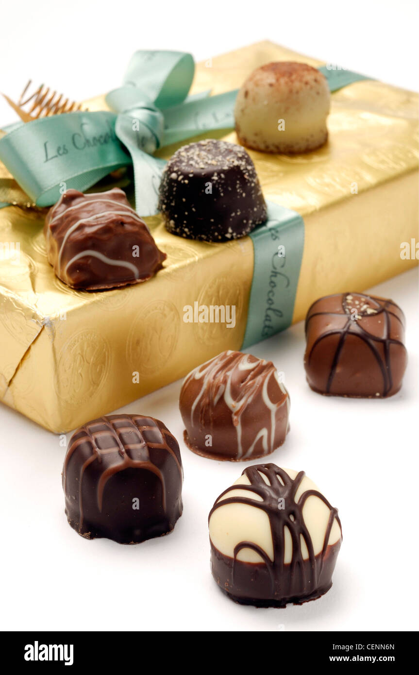 A box of chocolates wrapped in gold foil paper and tied green ribbon An