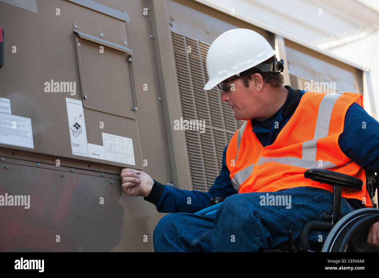Facilities engineer in a wheelchair opening inspection plate of commercial air conditioning system Stock Photo