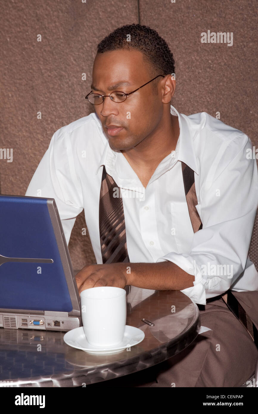 Businessman working notebook laptop computer sitting by the coffee table of some cafe outdoors Stock Photo