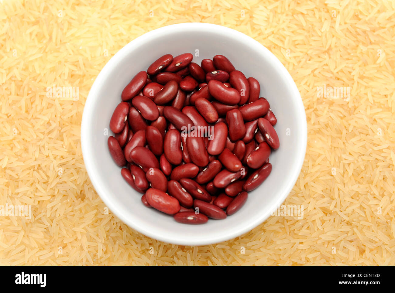 A white bowl of dried kidney beans surrounded by basmati rice Stock