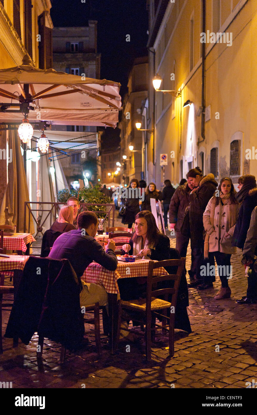 Diners at tables outside one of the restaurants in the Trastevere district of Rome in early spring. Stock Photo
