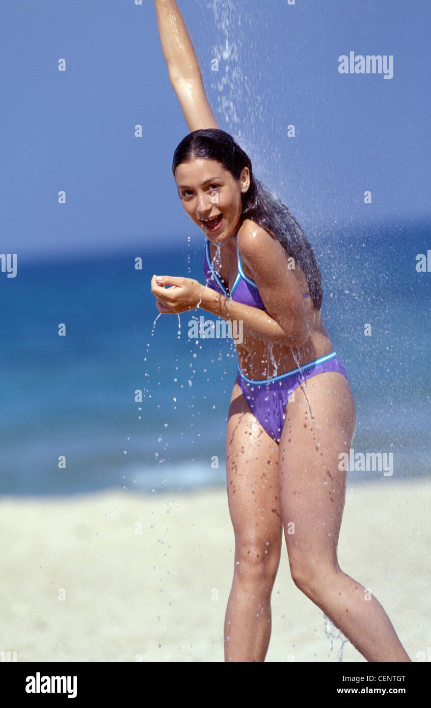 Female on beach wearing purple blue and white bikini, standing under shower  Stock Photo - Alamy