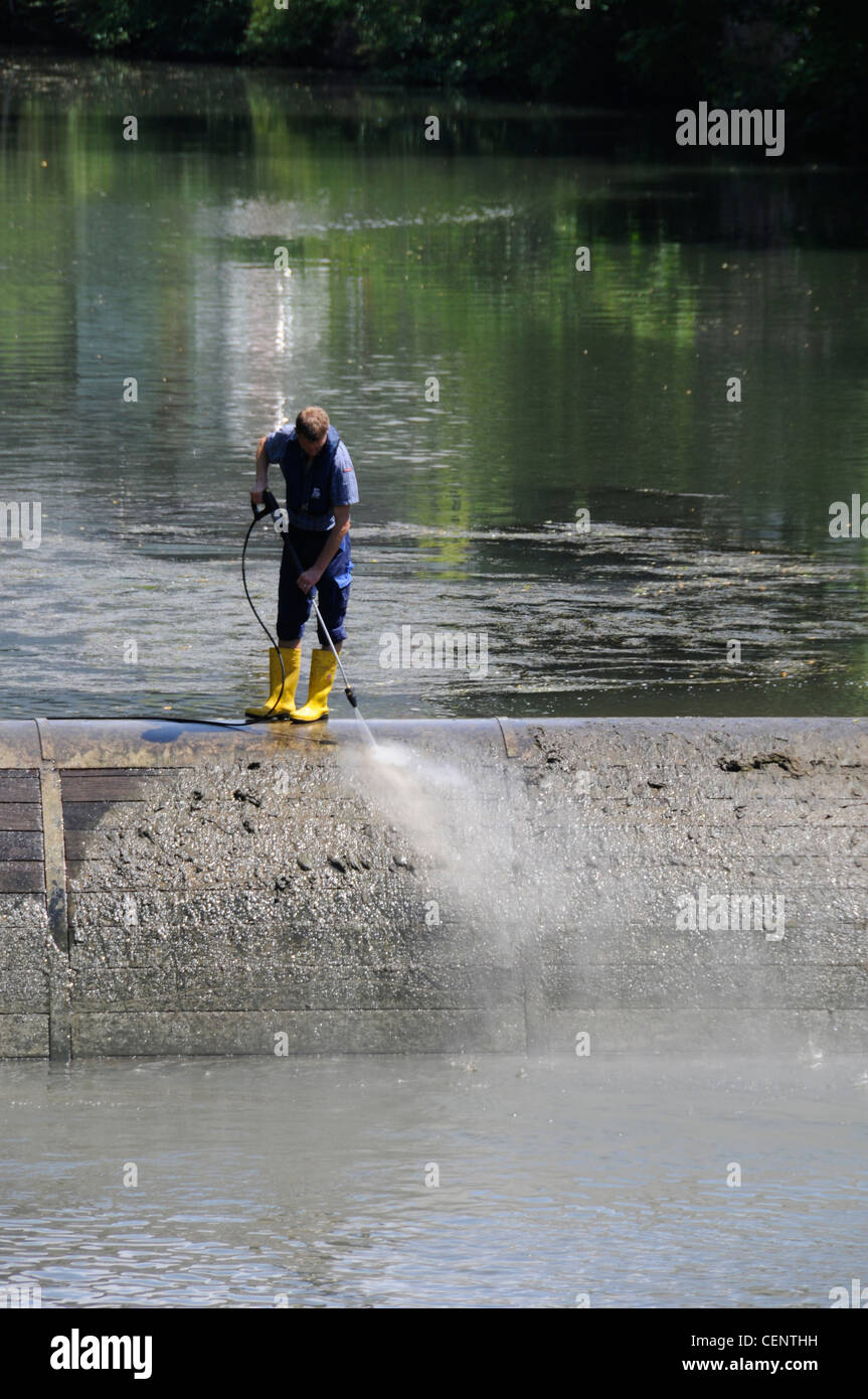 A council worker jet spray cleaning a water overflow on the river Pegnitz that flows through the centre of Nuremberg, Germany Stock Photo