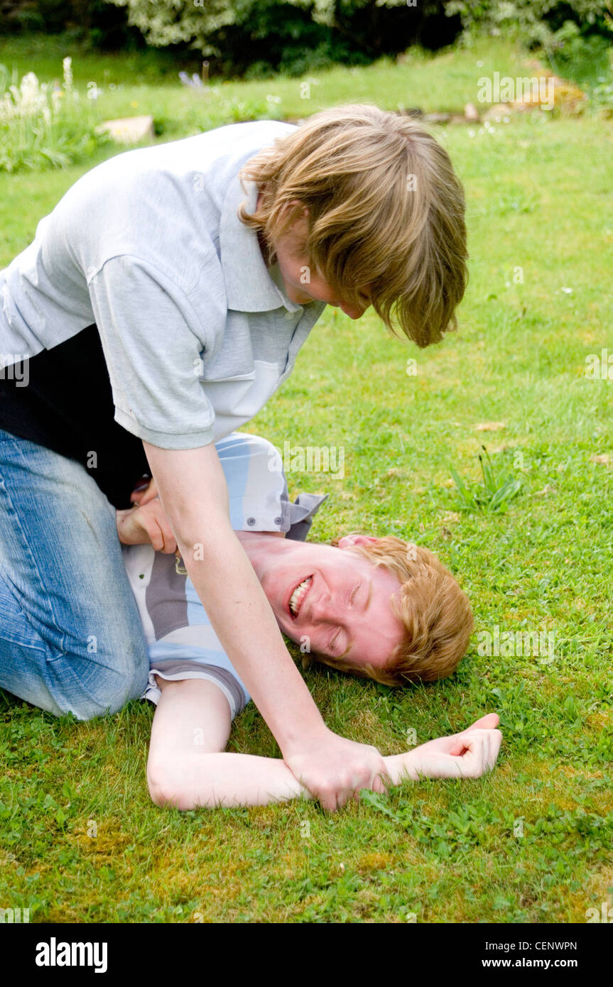 Two male teenagers play fighting in garden Stock Photo - Alamy