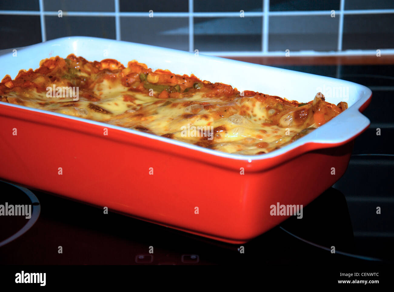 Bake lasagne in the red saucer. Stock Photo