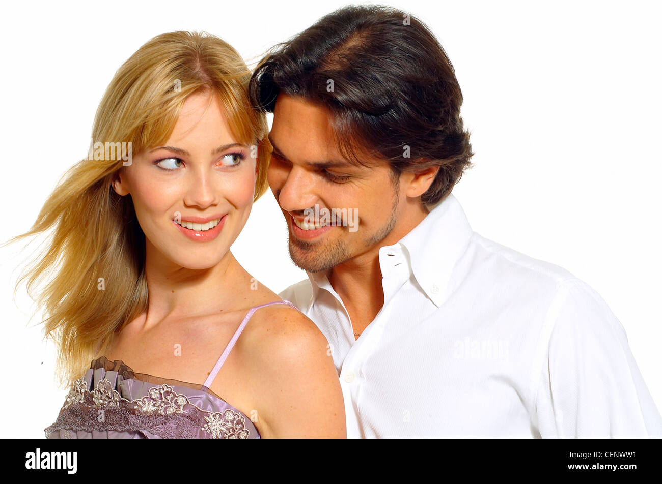 Female long blonde hair wearing lilac sleeveless top standing against male dark hair wearing white shirt looking at her Stock Photo