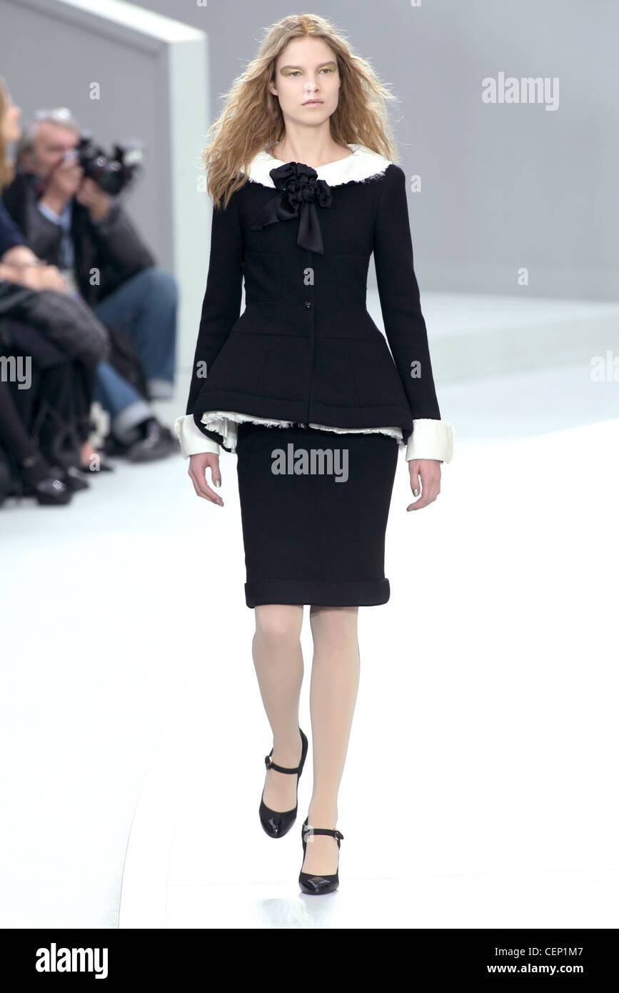 Chanel Paris Ready to Wear Autumn Winter Model wearing black skirt suit white contrast trim and corsage black Mary Jane shoes Stock Photo