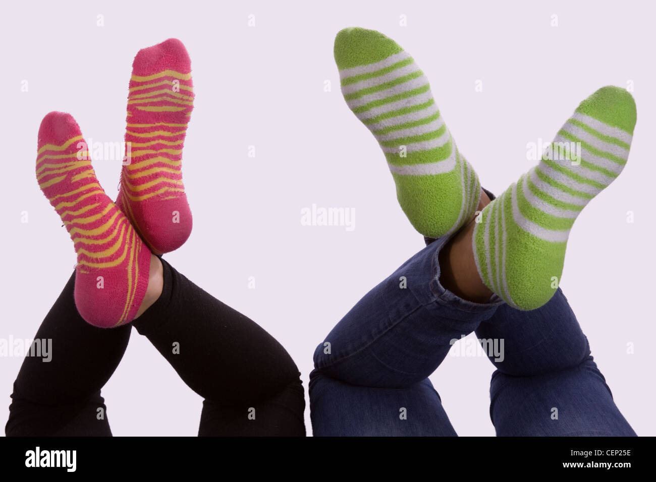 legs of two young girls feet wearing striped socks green and pink with