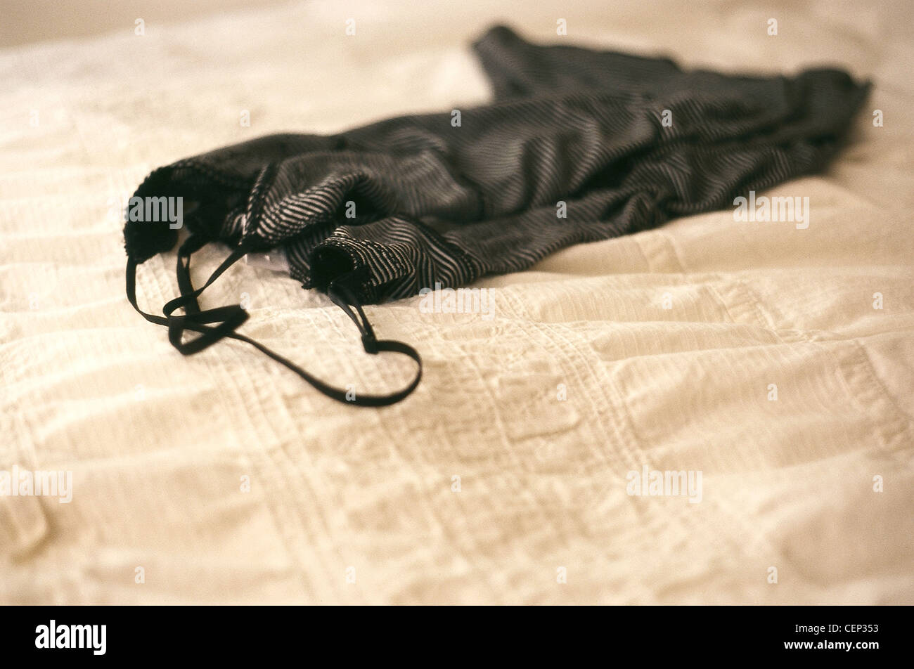 A black and white striped nightdress on a white textured bed spread Stock Photo