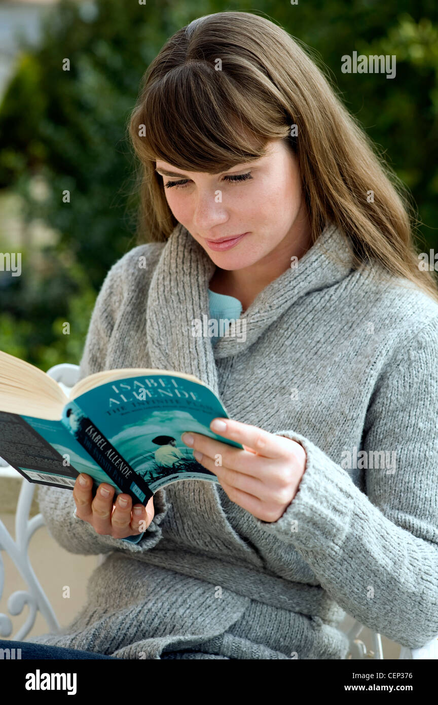 Female sitting outdoors reading a book Stock Photo - Alamy