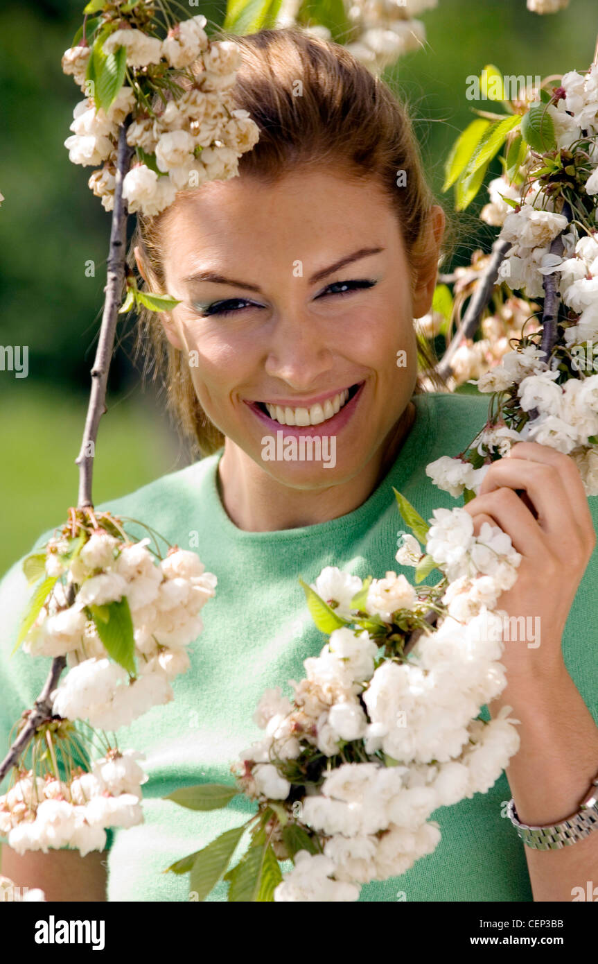 Female standing under cherry blossom tree holding branches Stock Photo ...
