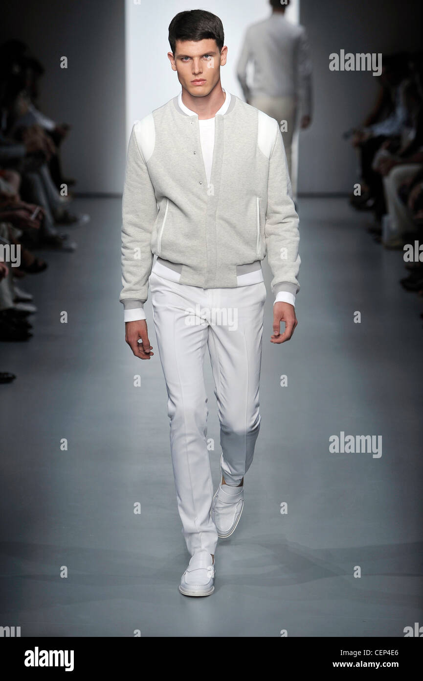 Calvin Klein Milan Ready to Wear Spring Summer Model wearing narrow legged white trousers, white t shirt, light grey and white Stock Photo