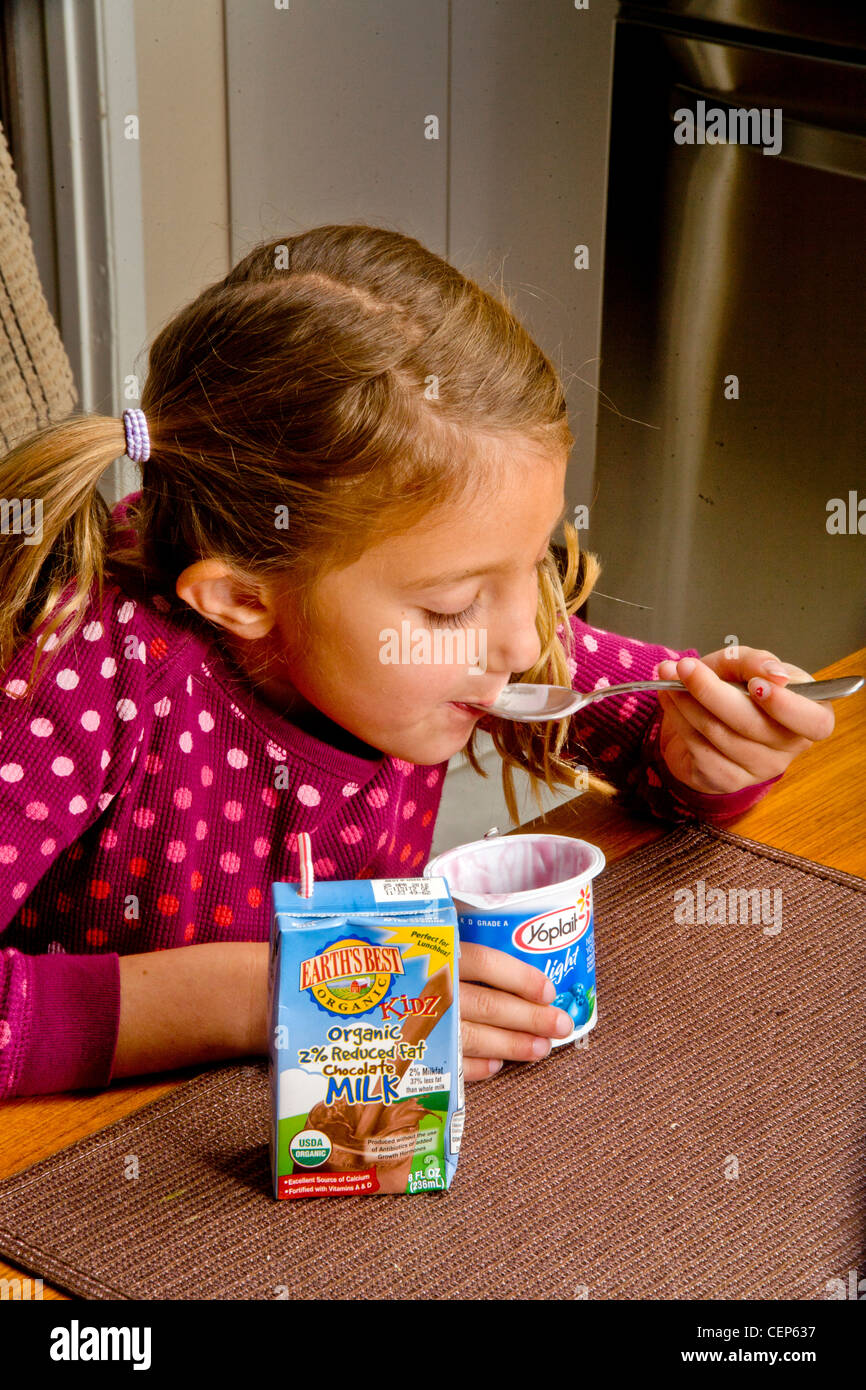 A 6 year old girl eats a healthy breakfast of low fat milk and yogurt at home in San Juan Capistrano, CA. MODEL RELEASE Stock Photo