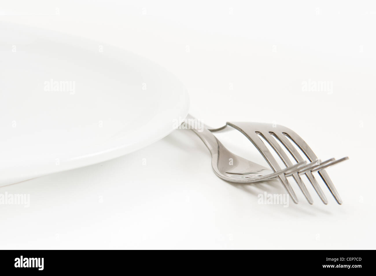 Beautiful fork and a white plate, a kitchen accessories close up Stock Photo