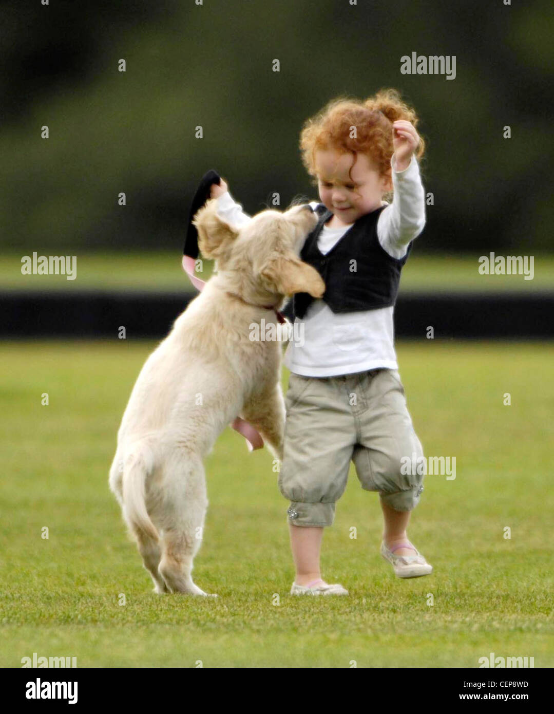Female child curly red hair, wearing a white top long sleeves, black waistcoat, pale green cropped trousers and white shoes, Stock Photo