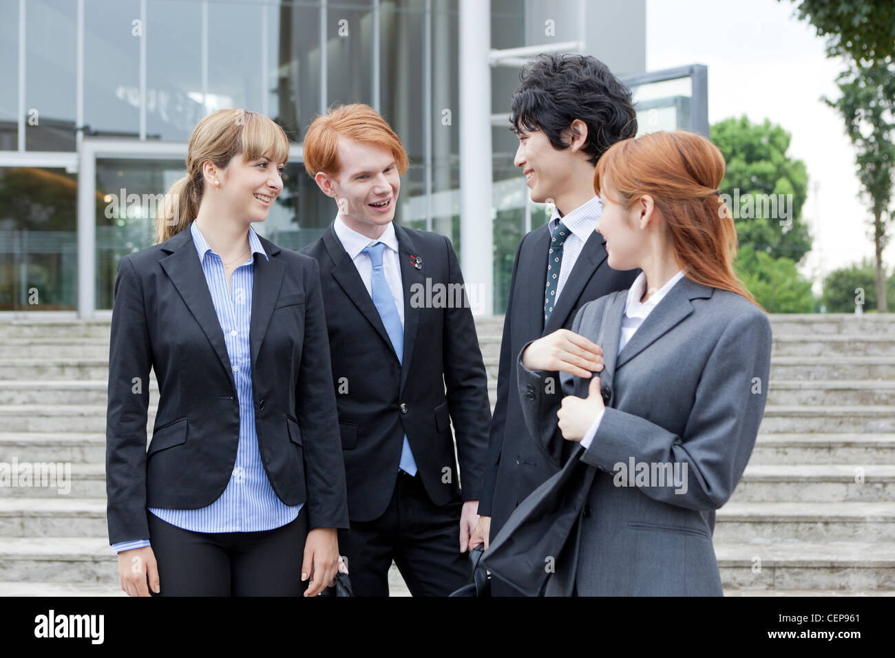 Businessmen and businesswomen talking in front of building Stock Photo