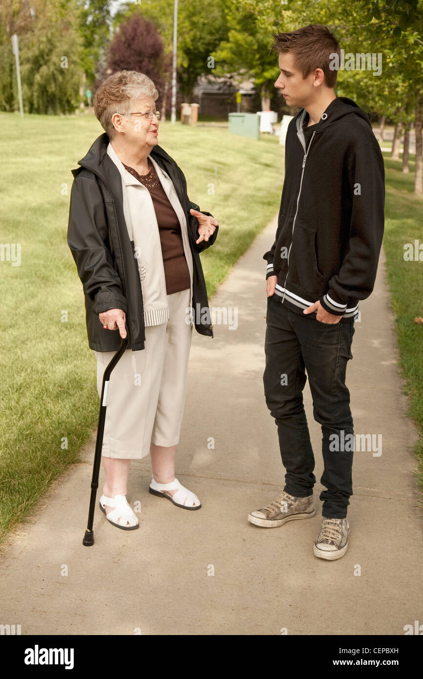 a senior woman talking with a teenage boy; edmonton, alberta, canada Stock Photo