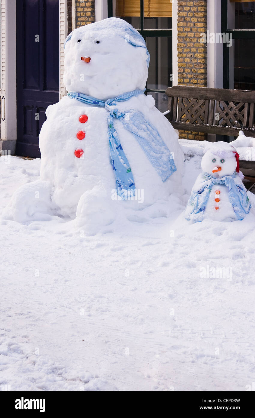 Funny Snowman and snowchild in front of house in the street - vertical image Stock Photo