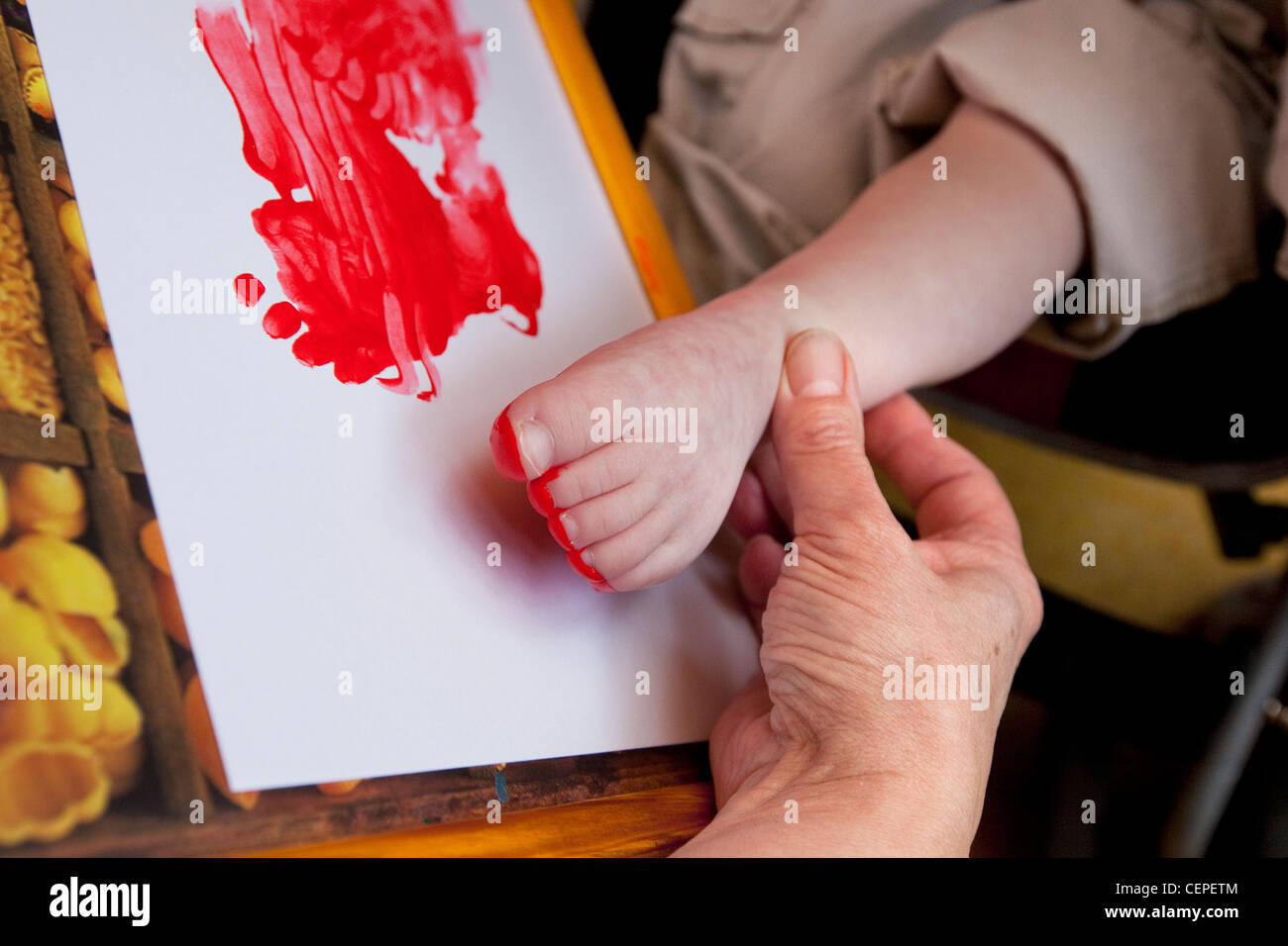 Child with learning disabilities using foot to paint a picture Stock Photo