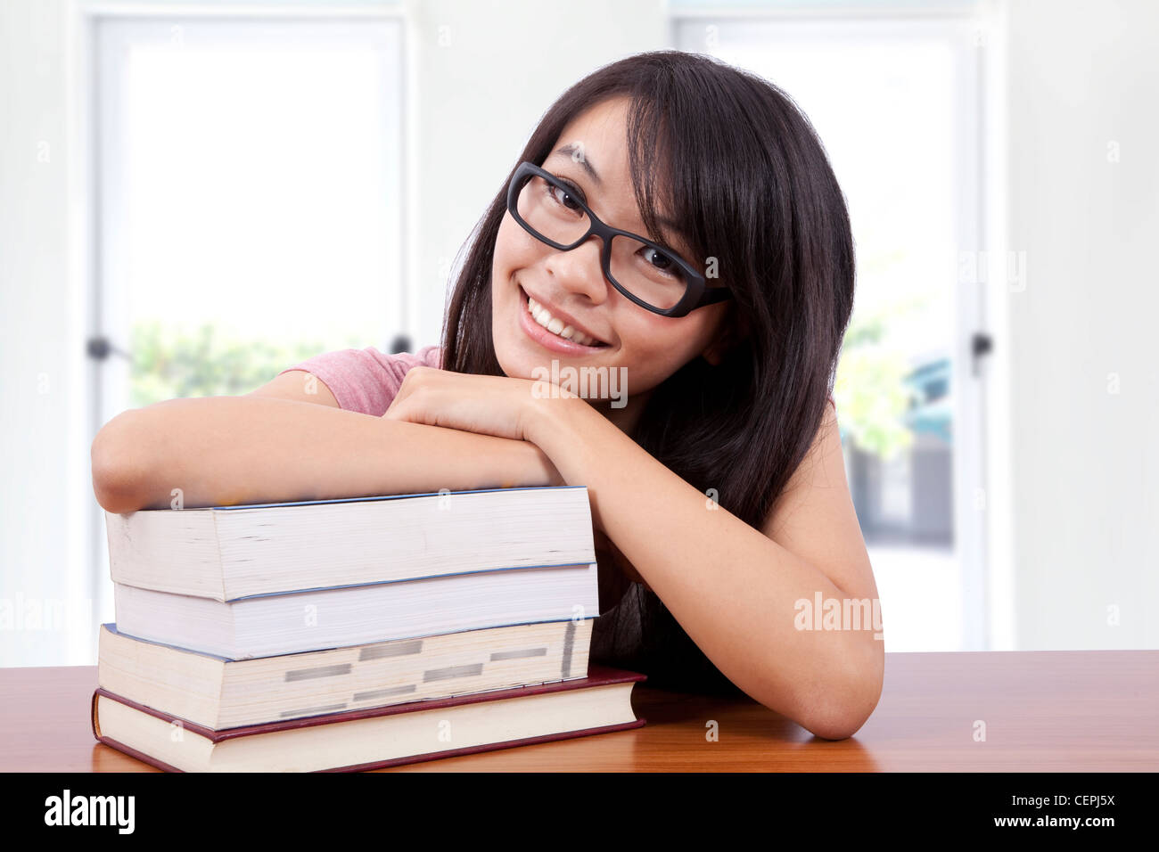 Beautiful smiling girl in a classroom with book Stock Photo - Alamy