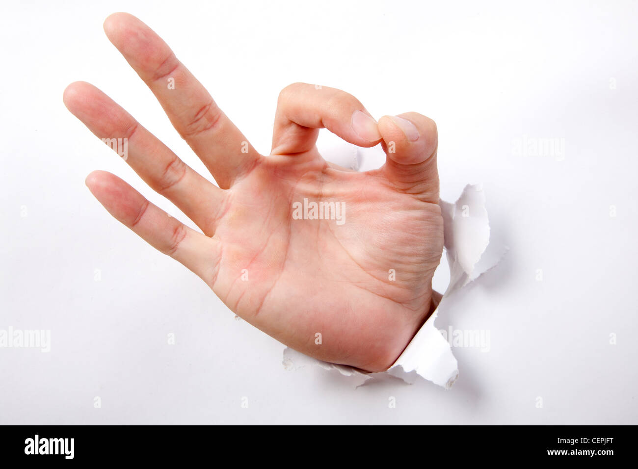 Hand punching through white paper and ok sign Stock Photo Alamy