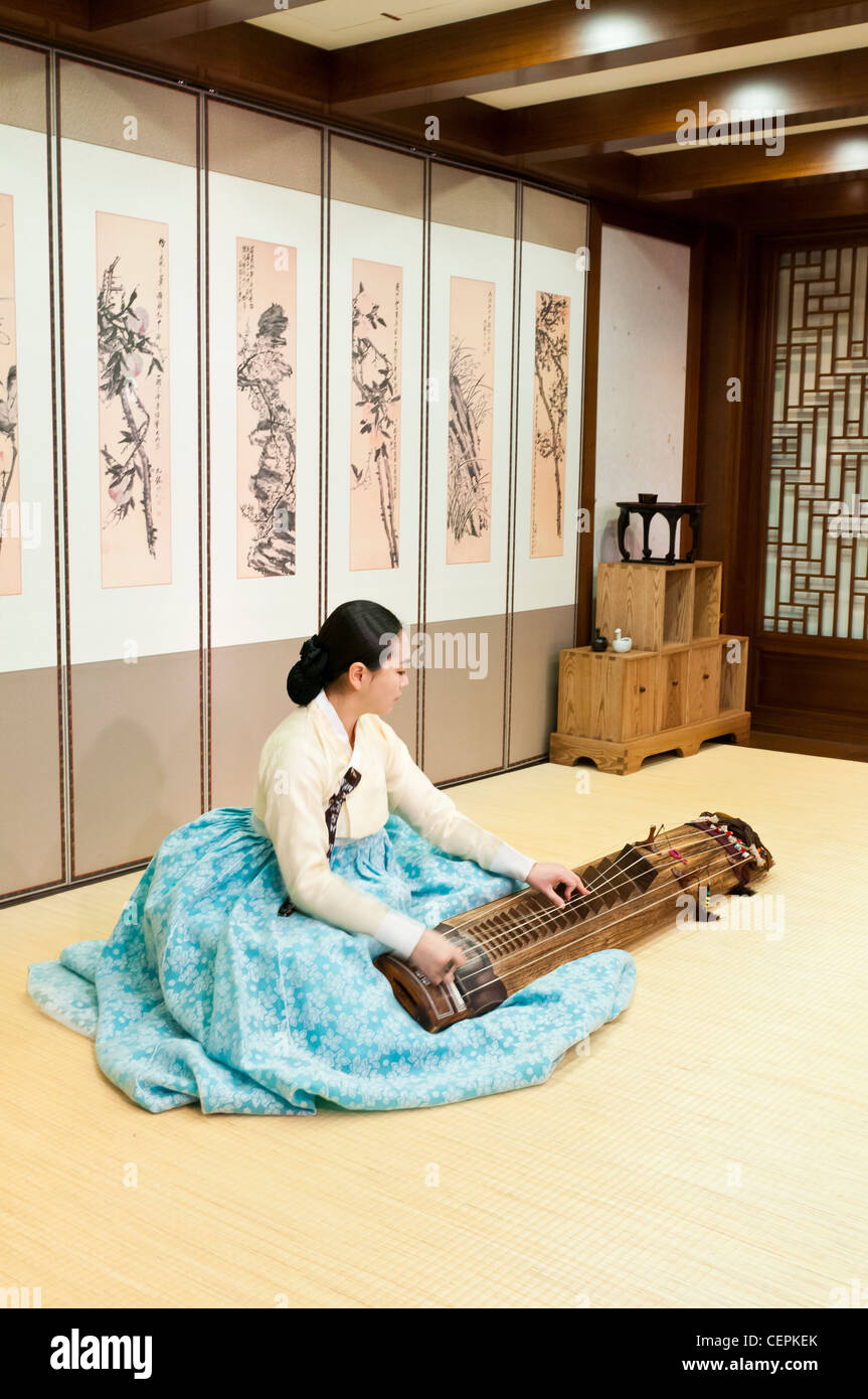 a young Korean woman playing a Korean traditional musical instrument gayageum or kayagum wearing Korean traditional costume Stock Photo