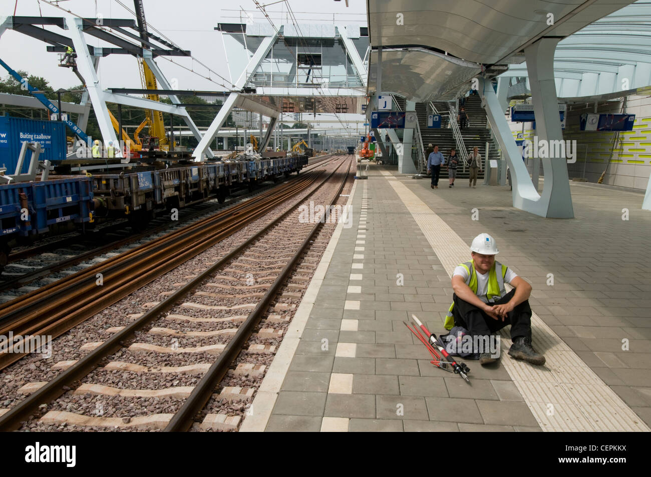 working man sitting, waiting at platform, Arnhem Centraal, railway station Arnhem, The Netherlands Stock Photo