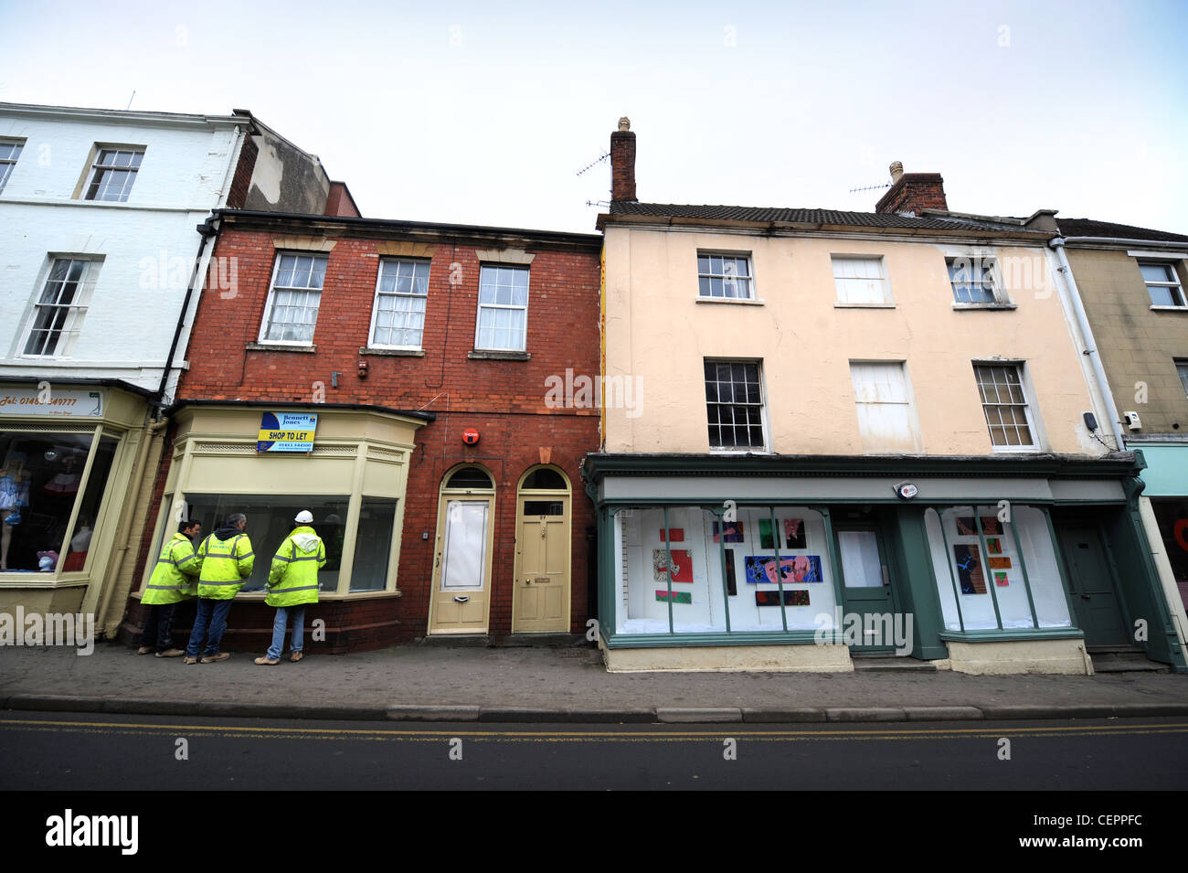Construction workers look into an unoccupied shop in temporary use as an art gallery in Dursley, Gloucestershire, UK Stock Photo