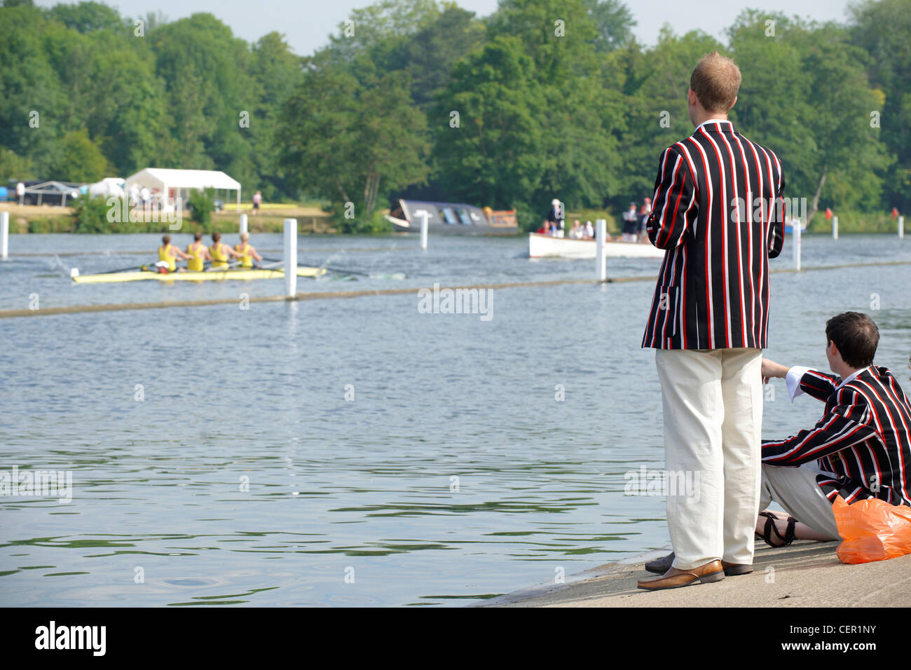 Spectators wearing rowing club blazers on the riverside watching a race at the annual Henley Royal Regatta. Stock Photo
