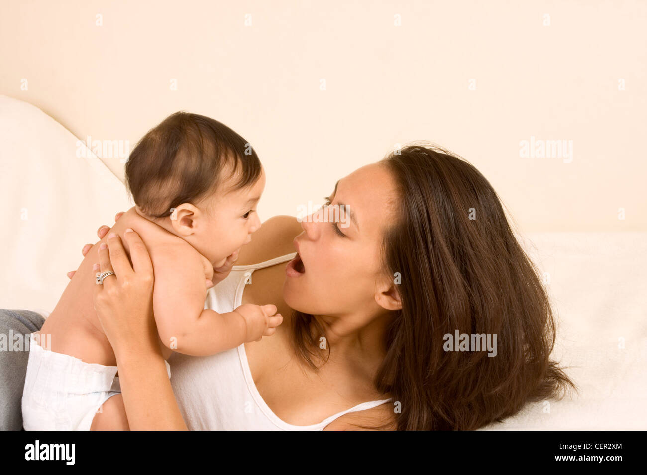 Mom and son on bed and mother embracing the infant baby playing with him Stock Photo