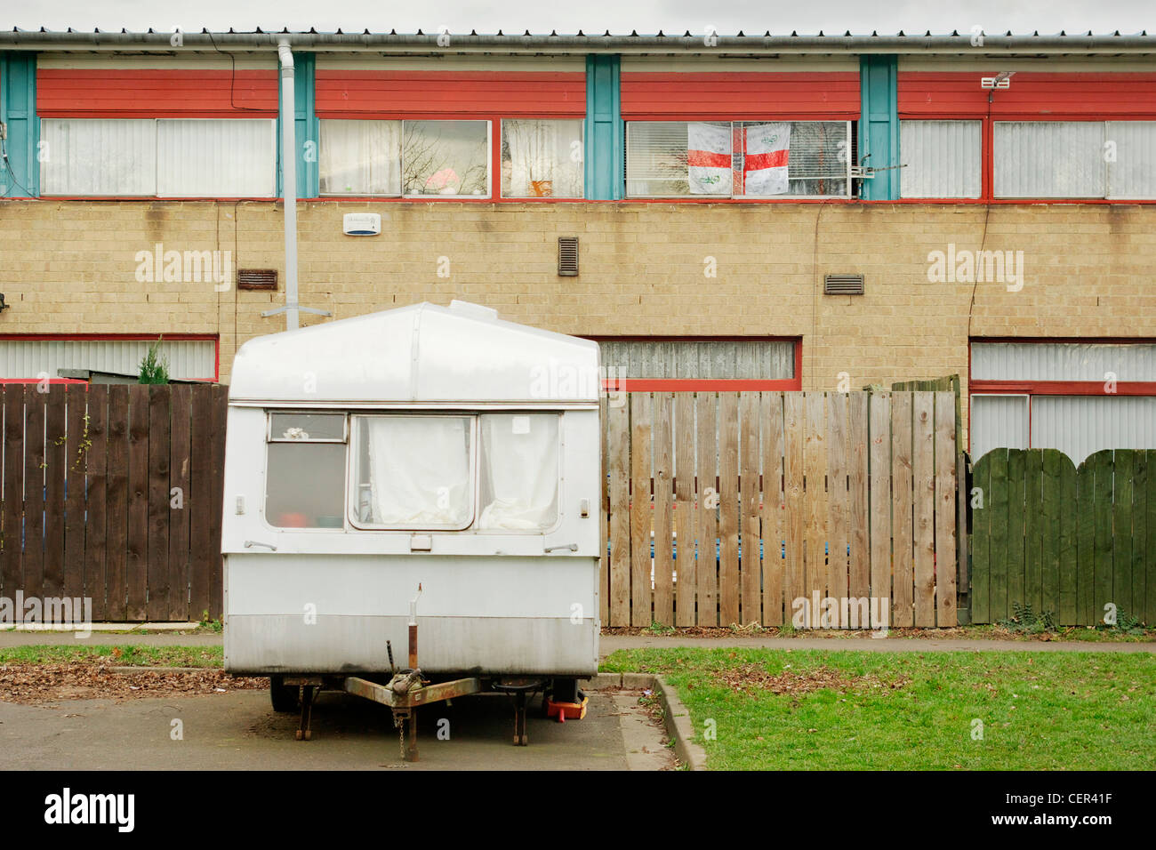 Old caravan outside council house with St. George’s flag in the window. Stock Photo