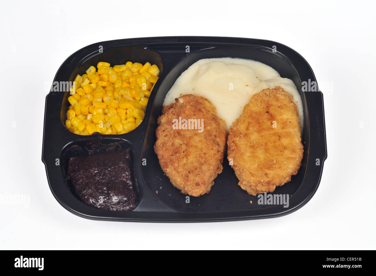 Fried chicken tv dinner with mashed potatoes and corn in black plastic disposable tray  on white background cut out. Stock Photo