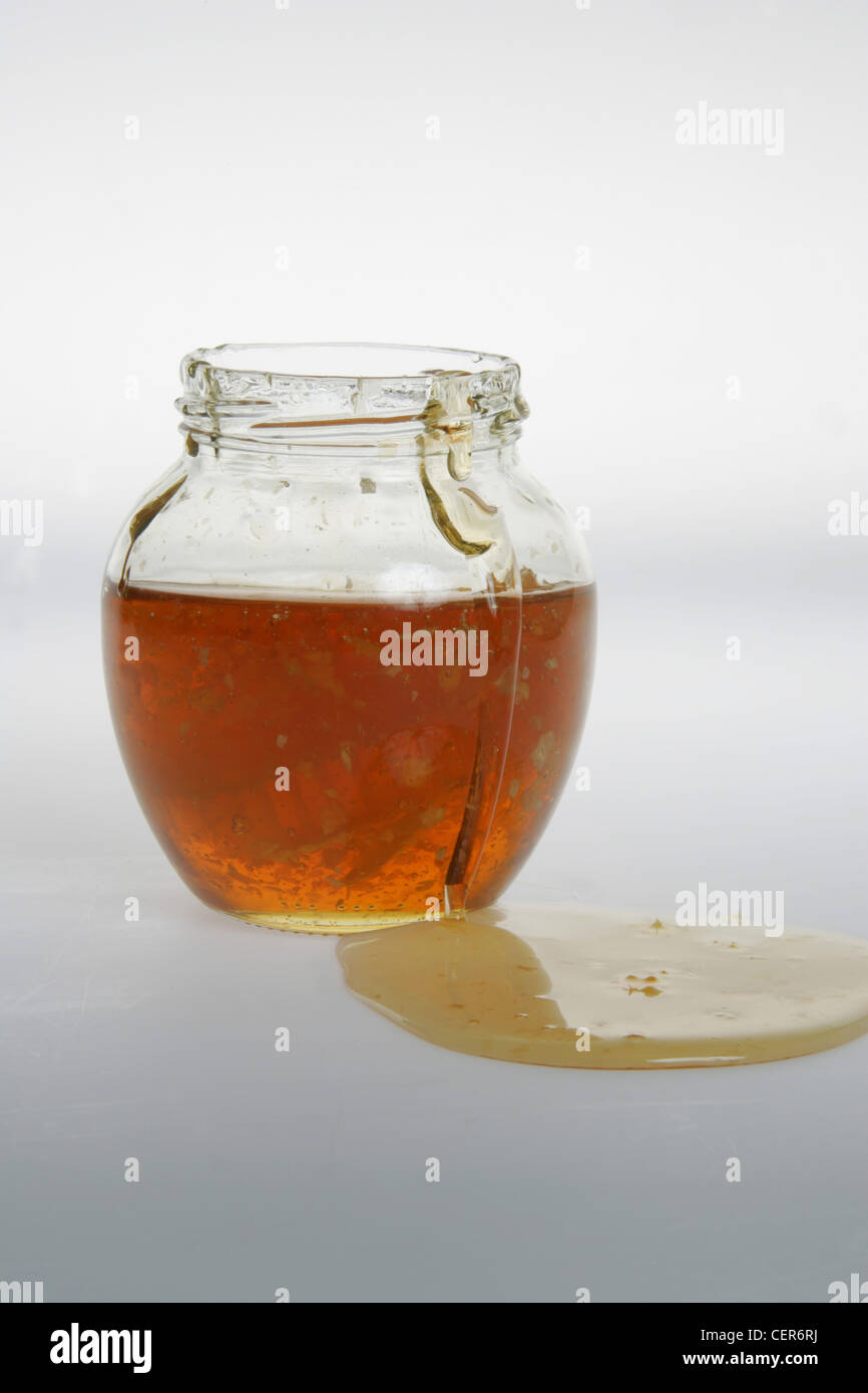 Honey in glass pot with honey in pool by side against white background Stock Photo Alamy