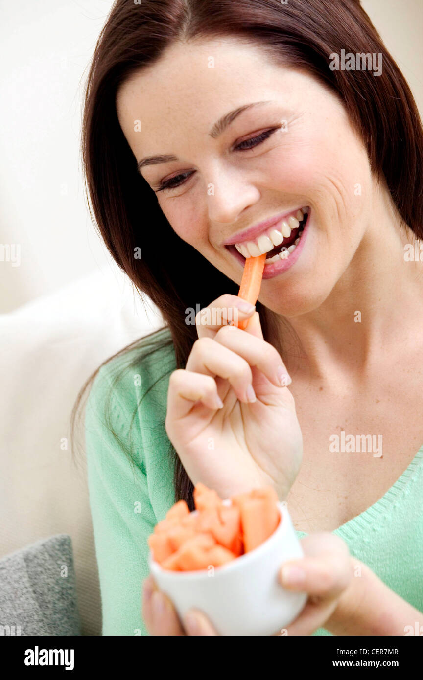 Female long hair wearing green v neck jumper, eating carrot
